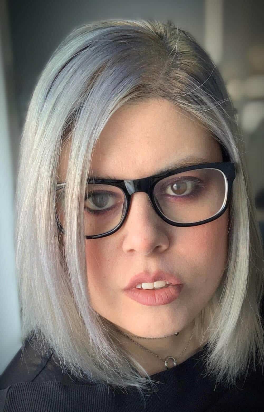 Maria looking straight into the camera, wearing glasses.